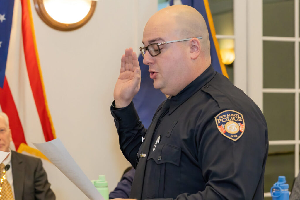 Police officer holding up his right hand while reading off a paper