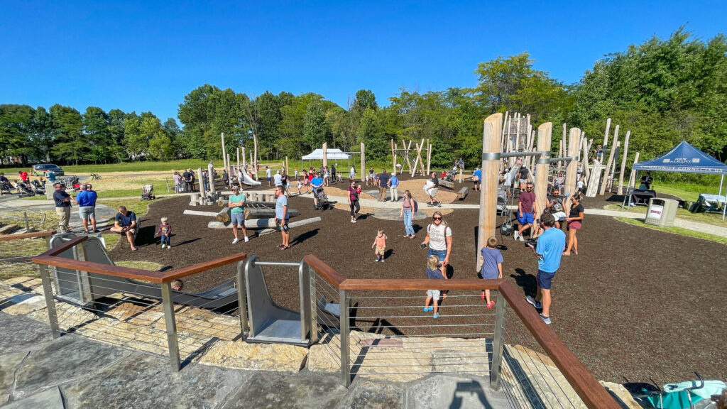 Outdoor playground filled with people, including children and adults, engaging in various activities.