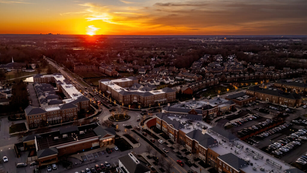 Aerial view of a suburban area at sunset with a mix of residential and commercial buildings.