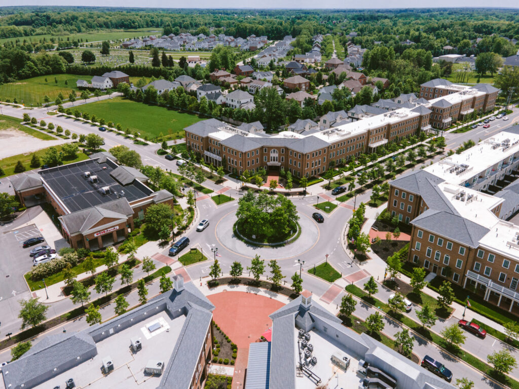 Aerial view of a suburban neighborhood with brick buildings and a circular roundabout surrounded by trees and greenery.