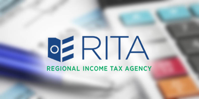RITA logo featuring a blue stylized icon and large blue letters 'RITA' with the green tagline 'Regional Income Tax Agency' over a blurred background of a pen, calculator keys, and tax forms.