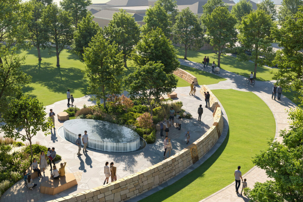 Curved stone-walled park plaza with oval reflecting fountain, trees, grassy paths, benches and people strolling.