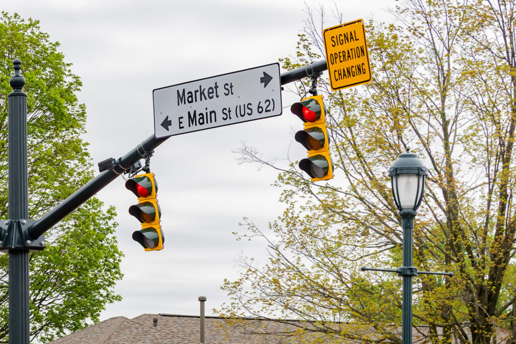 Street signs reading "Market St" and "E Main St (US 62)" with traffic lights and a yellow "Signal Operation Changing" sign visible