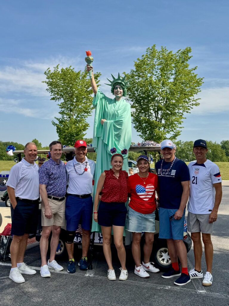 The seven city council members stand together outside during an Independence Day celebration