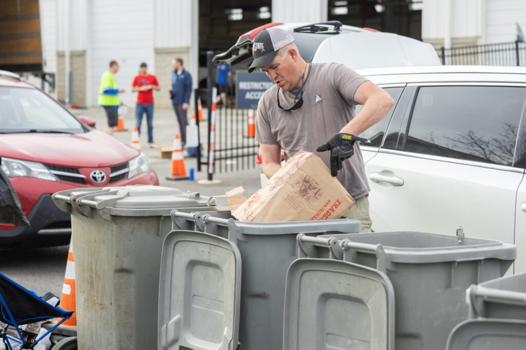 An individual dumping waste into a garbage can.