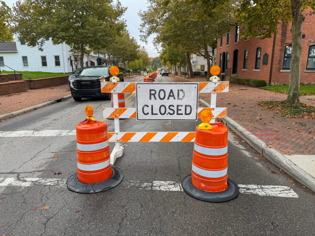 A "road closed" sign with two traffic barrels.