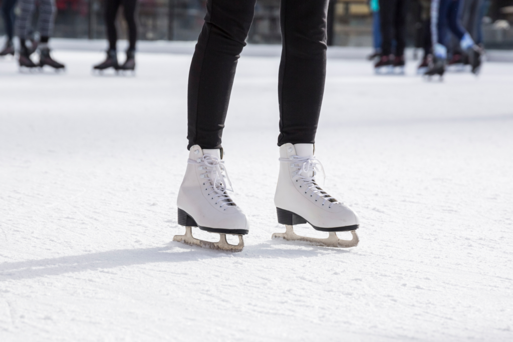 A person ice skating outside. It is a close up on the ice skates on the ice.